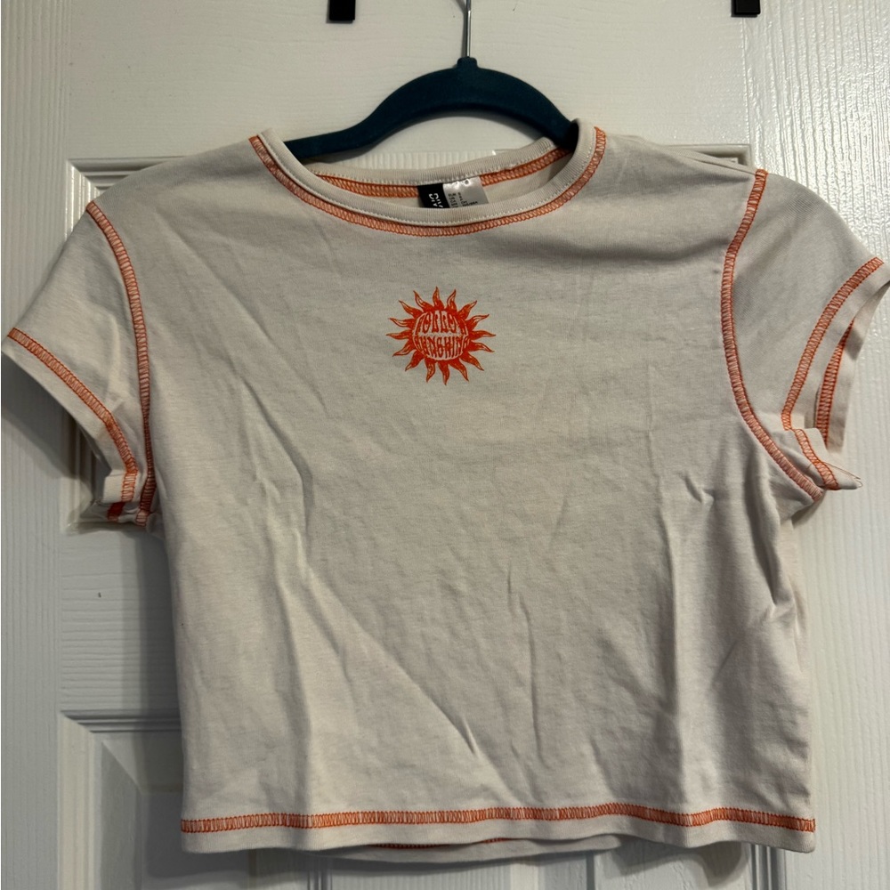 a beige with orange stitching cropped shirt